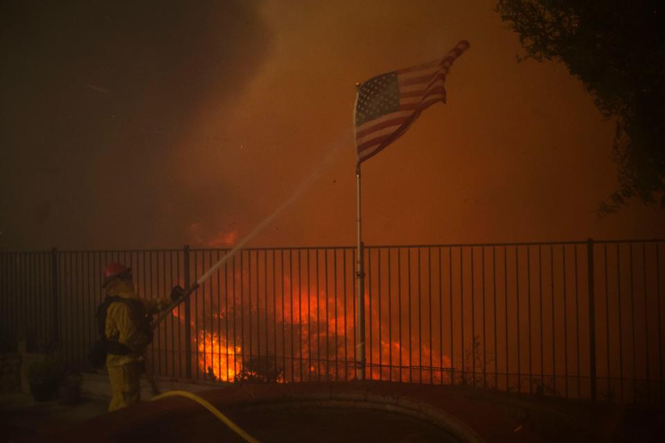 <p>A firefighter hoses down an American flag as flame reach the backyard of a home during the Holy Fire in Lake Elsinore, Calif., Aug. 9, 2018. (Photo: David McNew/EPA-EFE/REX/Shutterstock) </p>