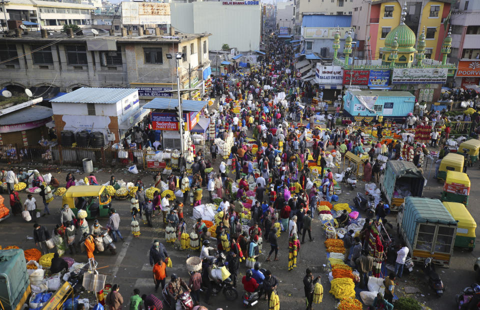 Shoppers crowd at a wholesale flower market in Bengaluru, India, Friday, Nov. 20, 2020. India's total number of coronavirus cases since the pandemic began has crossed 9 million. Nevertheless the country's new daily cases have seen a steady decline for weeks now. (AP Photo/Aijaz Rahi)