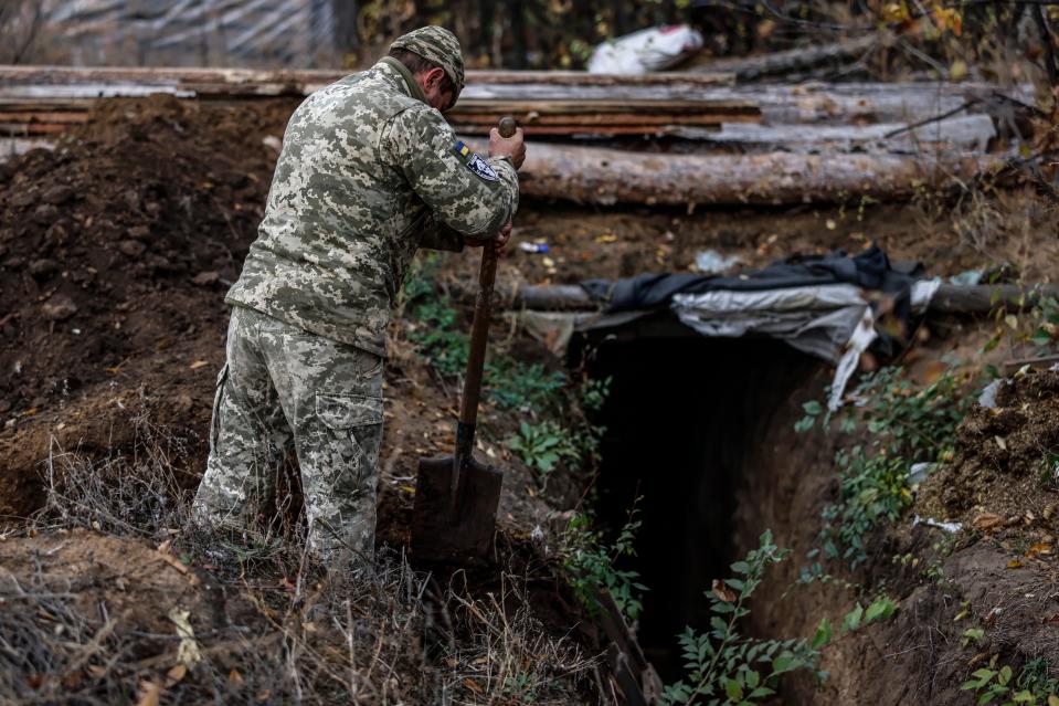 A Ukrainian soldier digs a trench by the dugout (EPA)
