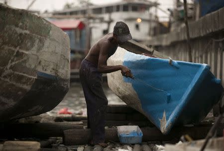 A man paints a boat he has repaired on a floating dock in Luar Batang in north Jakarta in this October 7, 2014 file photo. REUTERS/Darren Whiteside/Files