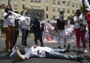 A doctor lies on the street as she allows blood to drip from her hand during a protest outside the Health Ministry headquarters in Lima, Peru, Wednesday, Jan. 13, 2021. Health workers are demanding better salaries and more personal protection equipment as they treat patients with the new coronavirus during the pandemic's second wave. (AP Photo/Martin Mejia)