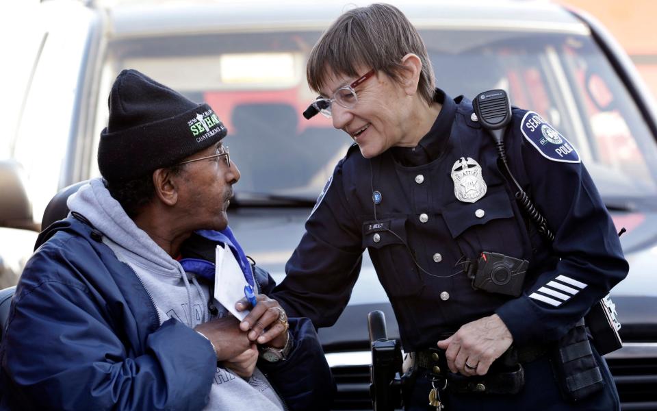 Seattle police officer Debra Pelich, right, wears a video camera on her eyeglasses as she talks with Alex Legesse before a small community gathering in Seattle - AP