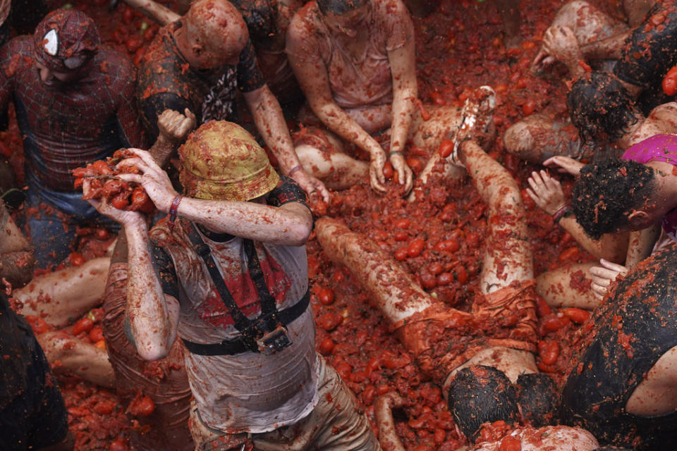 Revellers throw tomatoes at each other during the annual “Tomatina”, tomato fight fiesta, in the village of Bunol near Valencia, Spain, Wednesday, Aug. 30, 2023. Thousands gather in this eastern Spanish town for the annual street tomato battle that leaves the streets and participants drenched in red pulp from 120,000 kilos of tomatoes. (AP Photo/Alberto Saiz)