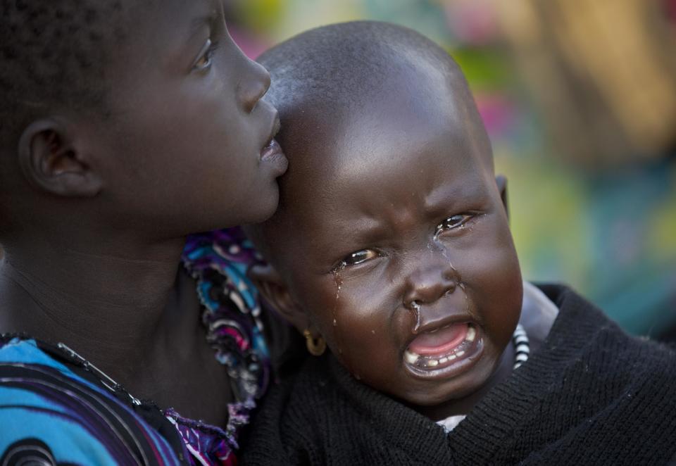 A displaced girl cries in the arms of a relative, one of the thousands who fled the recent fighting between government and rebel forces in Bor by boat across the White Nile, in the town of Awerial, South Sudan Thursday, Jan. 2, 2014. The international Red Cross said Wednesday that the road from Bor to the nearby Awerial area "is lined with thousands of people" waiting for boats so they could cross the Nile River and that the gathering of displaced is "is the largest single identified concentration of displaced people in the country so far". (AP Photo/Ben Curtis)