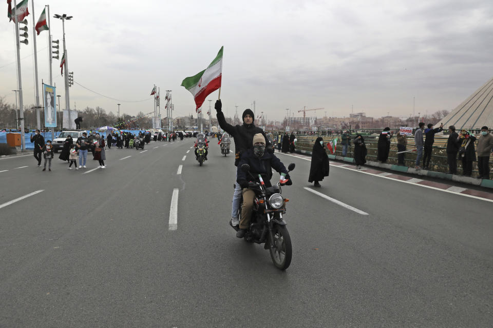 A man on a motorcycle holds a national flag during the annual rally commemorating the anniversary of1979 Islamic Revolution in Azadi (freedom) Sq. in Tehran, Iran, Friday, Feb. 11, 2022. Thousands of cars and motorbikes paraded in the celebration, although fewer pedestrians were out for a second straight year due to concerns over the coronavirus pandemic. (AP Photo/Vahid Salemi)