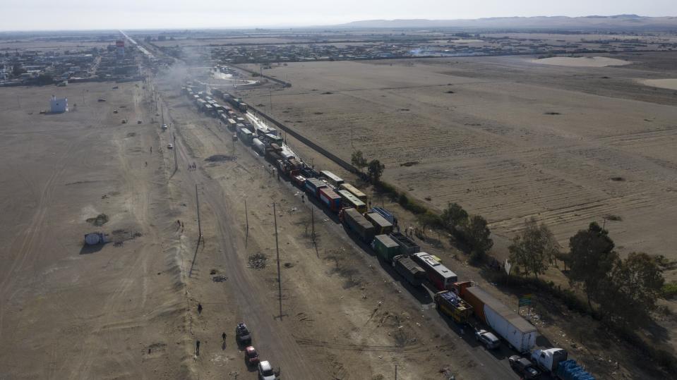 Trucks sit idle on the Pan-American South Highway during a blockade set up by farmworkers, on the fourth day of protests against the Agricultural Promotion Law, in Villacuri, Ica province, Peru, Thursday, Dec. 3, 2020. The farmworkers are asking for the elimination of the law, demanding better wages and health benefits. (AP Photo/Rodrigo Abd)