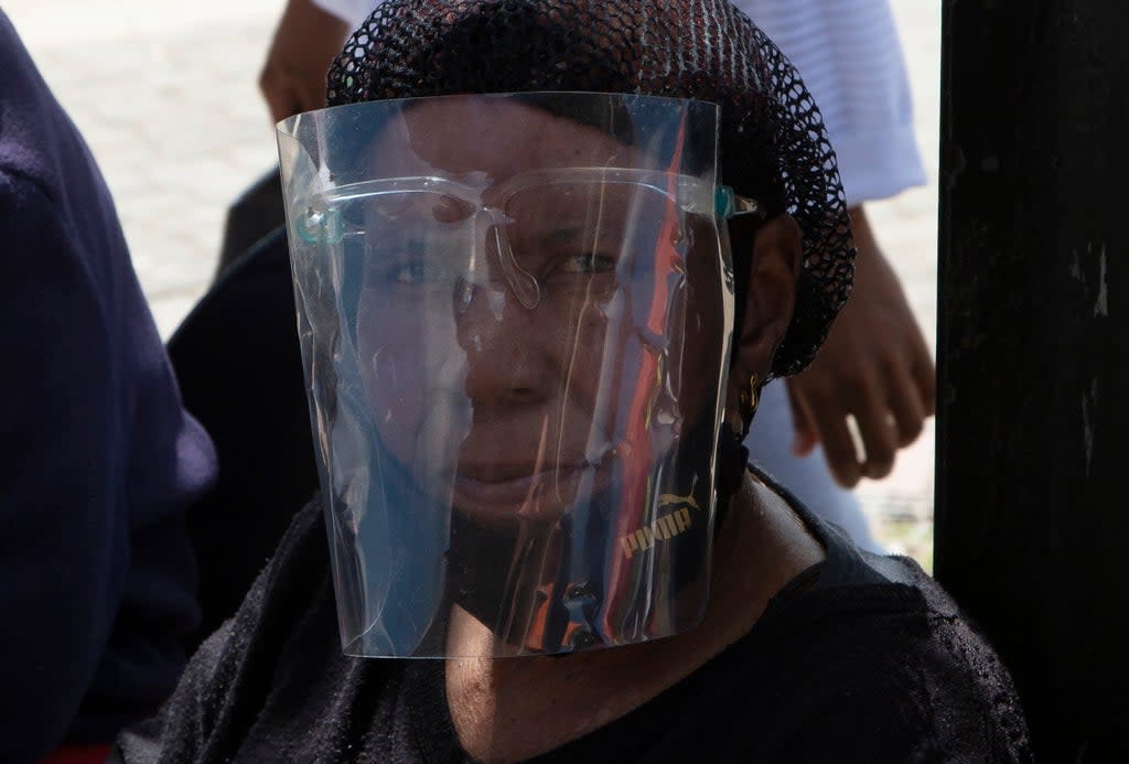 A woman wears a face shield to protect against COVID-19 at a taxi rank in Soweto, South Africa (AP)