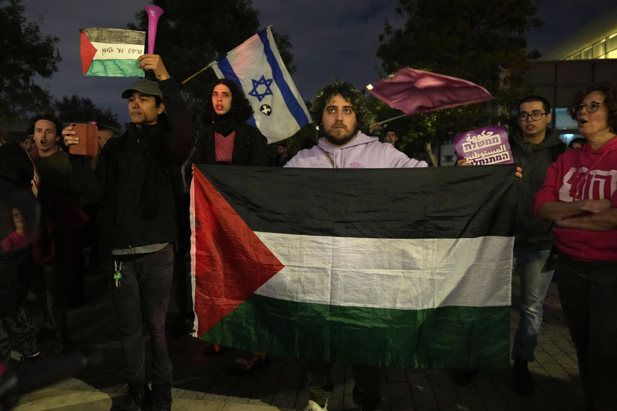 A protester holds a Palestinian flag in Tel Aviv, Israel, at a demonstration against Prime Minister Benjamin Netanyahu's far-right government, Saturday, Jan. 7, 2023. Thousands of Israelis protested plans by Netanyahu's government that opponents say threaten democracy and freedoms. (AP Photo/ Tsafrir Abayov)