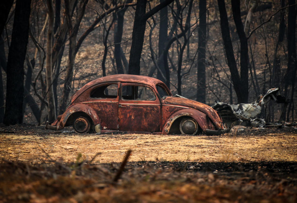 The remains of a car that was destroyed by bushfires sits near a home in the town of Balmoral on December 30. Source: Getty
