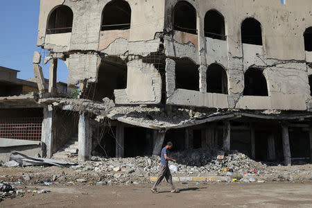 A man walks by a destroyed building in eastern Mosul, Iraq, April 19, 2017. REUTERS/Marko Djurica