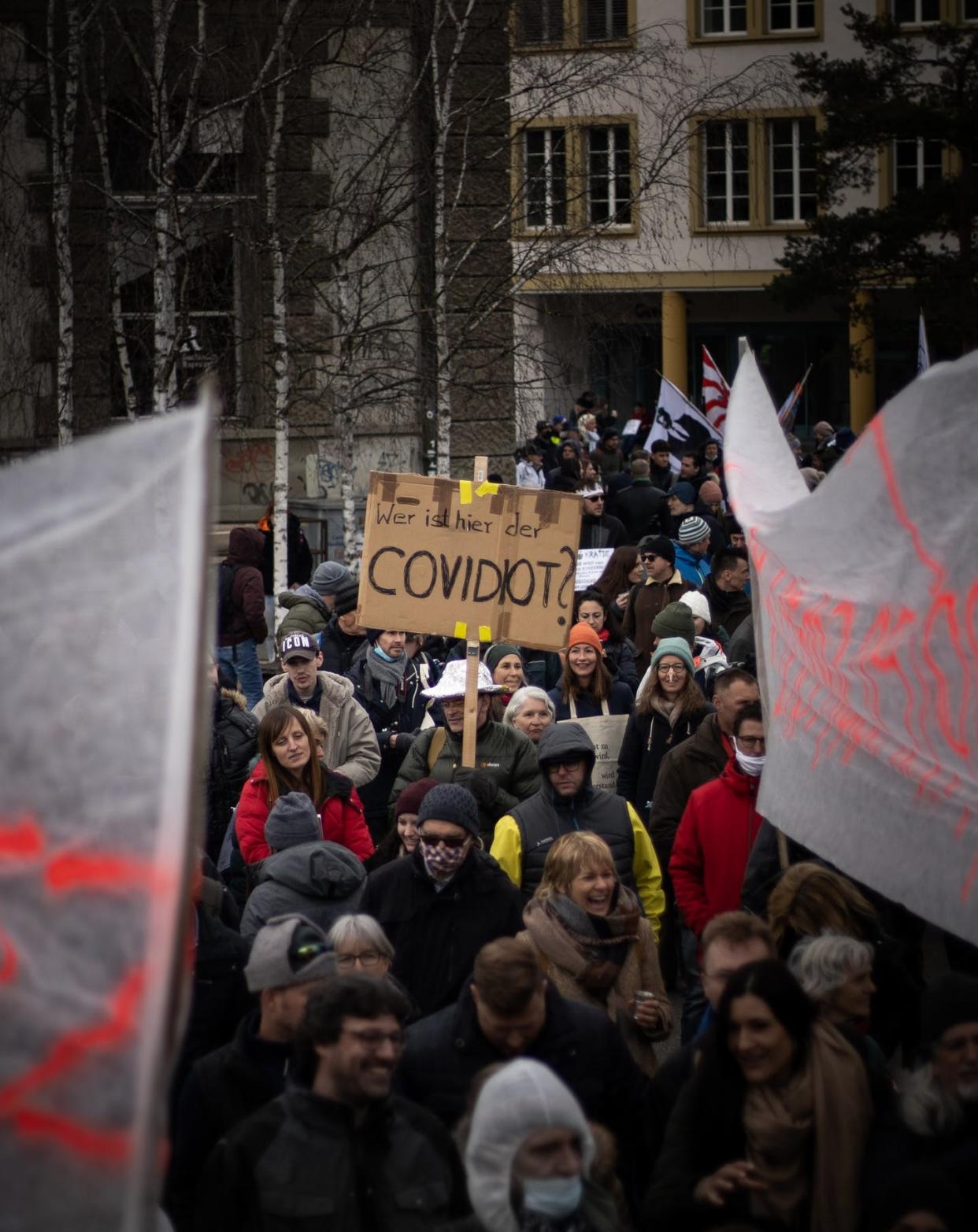 <span class="caption">Man holds sign reading 'wer ist hier der COVIDIOT' which means 'who is the COVIDIOT here?' at a protest against pandemic restrictions in March, 2021. </span> <span class="attribution"><span class="source">(Kajetan Sumila/Unsplash)</span></span>