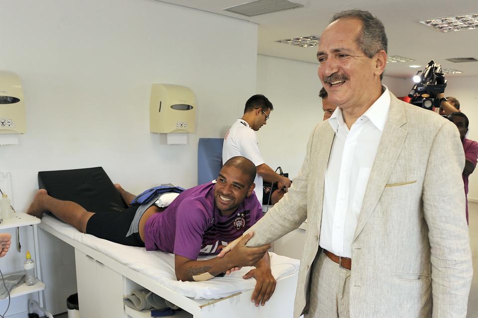 Brazil's Sports Minister Aldo Rebelo, right, greets soccer player Adriano during his visit to club Atletico Paranaense training certer in Curitiba, Brazil, Wednesday, Feb. 5, 2014. According Minister Rebelo, Curitiba is expected to remain in the World Cup despite stadium construction delays. The Arena da Baixada stadium, being built in Curitiba by Brazilian club Atletico Paranaense, is scheduled to host Iran-Nigeria on June 16, Australia-Spain on June 23, Algeria-Russia on June 26 and Honduras-Ecuador on June 30. (AP Photo/Denis Ferreira Netto)