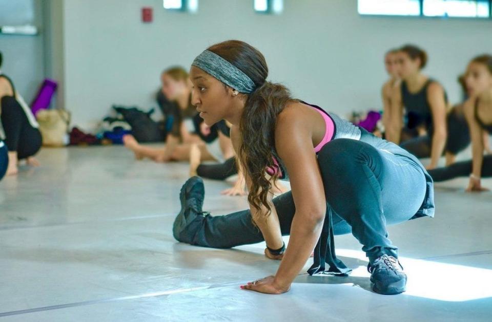 Saleemah E. Knight stretches with one leg extended out during a master class.