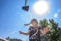 Water comes crashing down from a bucket directly on top of Jaecee Adams, 7, of Orofino, as she plays at the Orofino Splash Pad in Orofino, Idaho on Wednesday, June 30, 2021. (August Frank/The Lewiston Tribune via AP)