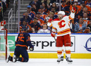 Calgary Flames forward Elias Lindholm, right, celebrates his goal as Edmonton Oilers defenseman Darnell Nurse kneels on the ice during the second period of Game 4 of an NHL hockey Stanley Cup playoffs second-round series Tuesday, May 24, 2022, in Edmonton, Alberta. (Jeff McIntosh/The Canadian Press via AP)