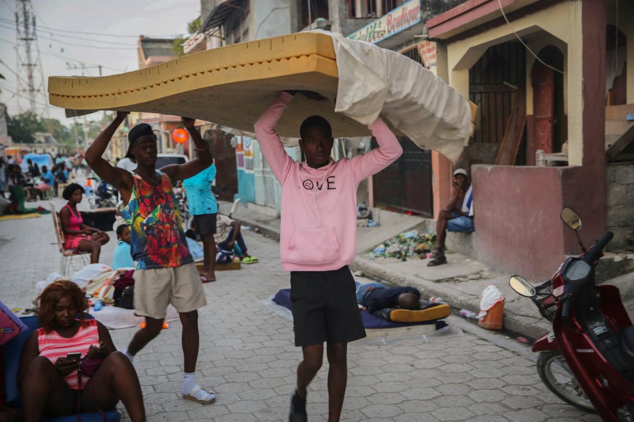 Men carry a mattress as people sleep on the streets after Saturday's  7.2 magnitude earthquake in Les Cayes, Haiti, Sunday, Aug. 15, 2021.