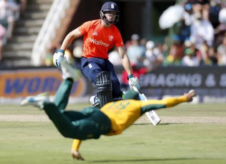 England's Jos Buttler runs between the wicket as South Africa's Imran Tahir dives for the ball during their second T20 international cricket match in Johannesburg, February 21, 2016. REUTERS/Sydney Seshibedi