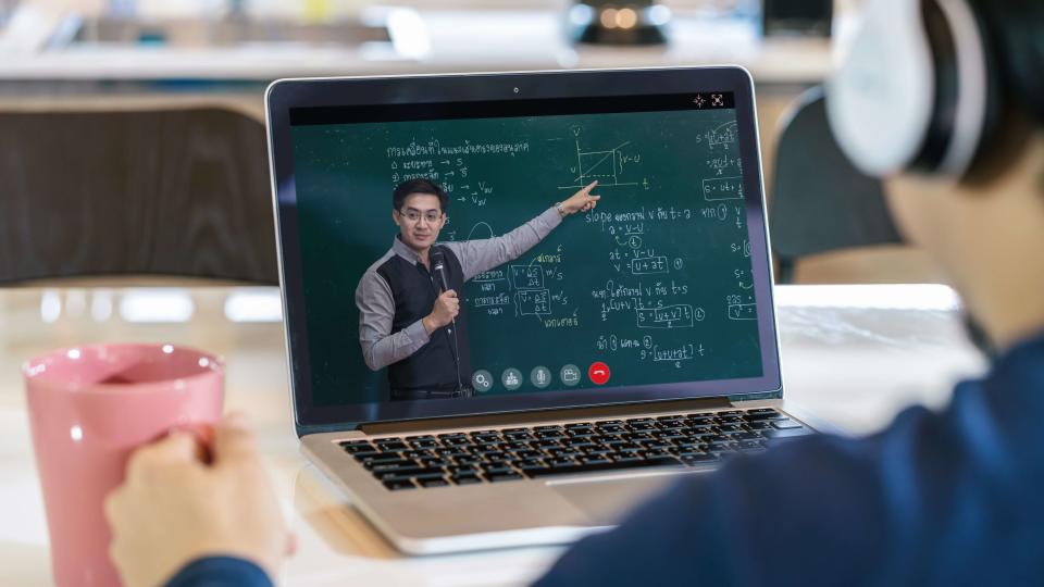 Rear View of Asian student learning with teacher on black board via video call conference when Covid-19 pandemic, education and Social distancing concept.