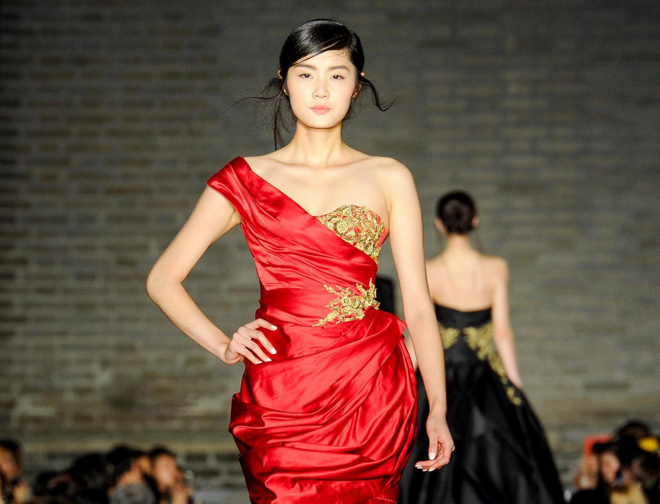 This June 2013 photo released by Council of Fashion Designers of America (CFDA) shows a model wearing a red Marchesa gown with gold embroidery during a fashion show by New York-based designers in Beijing, China. Rag & Bone, Marchesa and Proenza Schouler, among the top in their class of cool, youngish New York-based fashion houses, took a field trip to China recently to introduce themselves to Chinese consumers and to bring home a better understanding of their needs. (AP Photo/Council of Fashion Designers of America, Neil Rasmus)