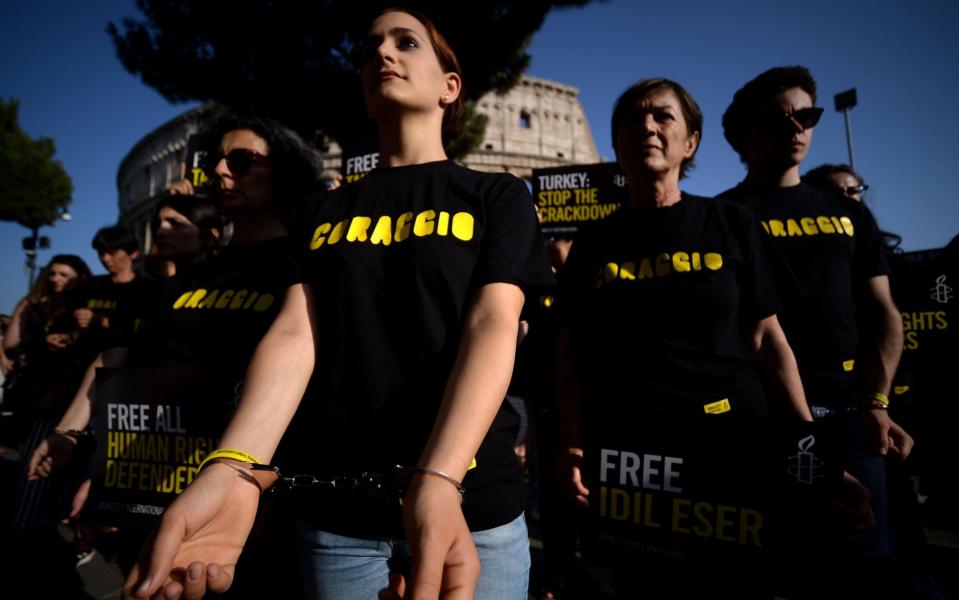 Amnesty International activists wear handcuffs as they protest against the arrest of rights activists in Turkey, including Amnesty International's Turkey director, on July 20, 2017, near the Coliseum in Rome - AFP