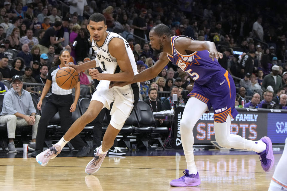 San Antonio Spurs center Victor Wembanyama (1) drives on Phoenix Suns forward Kevin Durant during the second half of an NBA basketball game Thursday, Nov 2, 2023, in Phoenix. (AP Photo/Rick Scuteri)