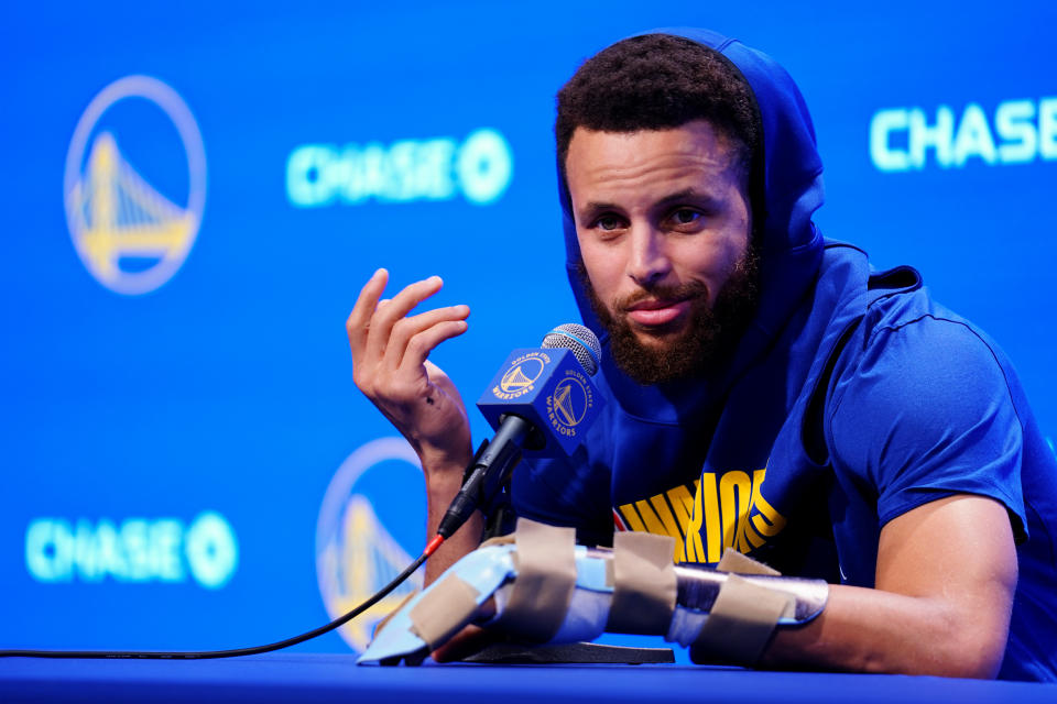 Stephen Curry, wearing a prominent brace on his broken hand, vowed to return this season.(Daniel Shirey/Getty Images)