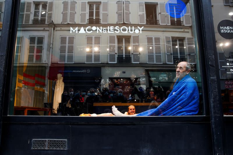 French actors perform a play behind store window in Paris