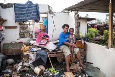 Fijian woman Kalisi holds her son Tuvosa, 3, as she sits on a bed in the remnants of her home damaged by Cyclone Winston in the Rakiraki District of Fiji's Ra province, February 24, 2016. REUTERS/UNICEF-Sokhin