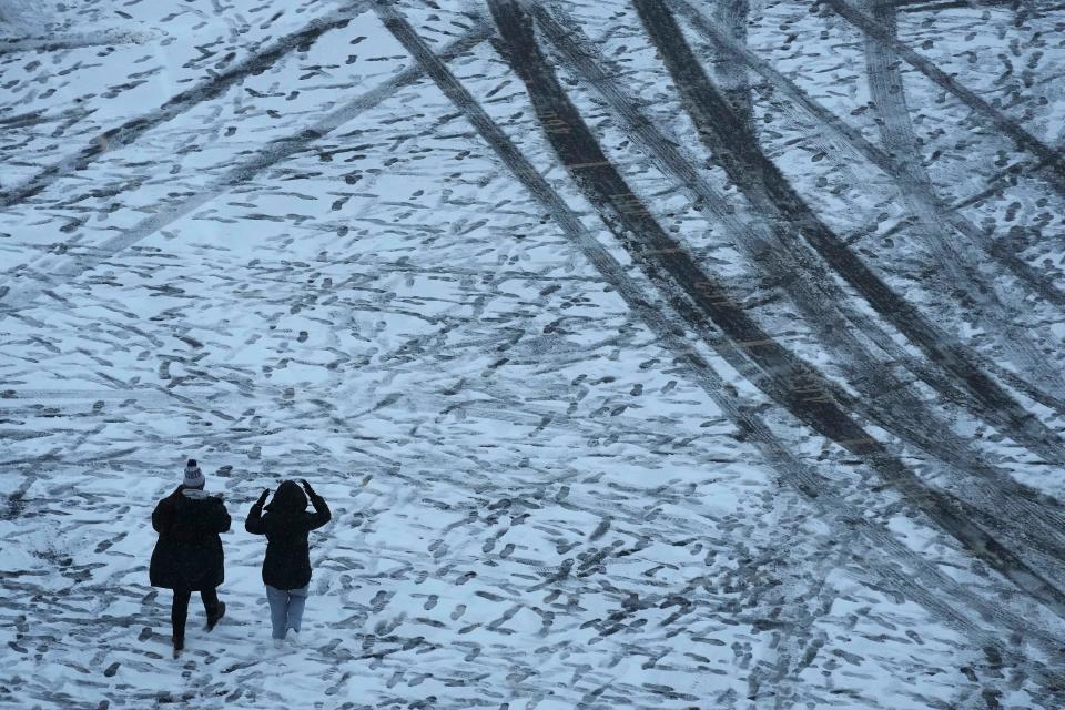 People walk through a parking lot after a winter storm dumped about 4 inches of snow on the area Nov. 25, 2023, in Manhattan, Kan.