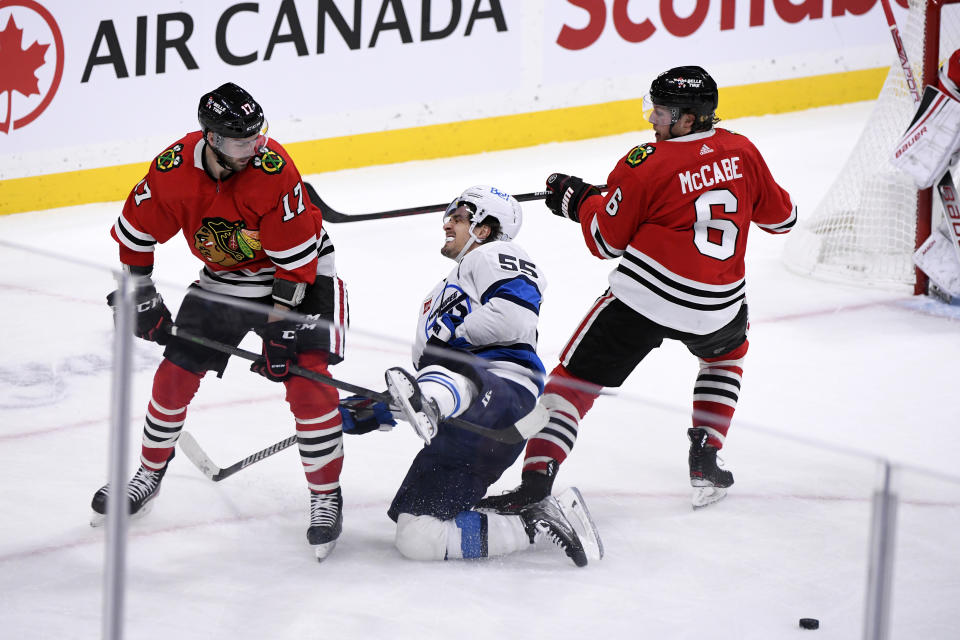 Winnipeg Jets' Mark Scheifele (55) is checked by Chicago Blackhawks' Jason Dickinson (17) and Jake McCabe (6) during the third period of NHL hockey game action in Winnipeg, Manitoba, Saturday, Nov. 5, 2022. (Fred Greenslade/The Canadian Press via AP)
