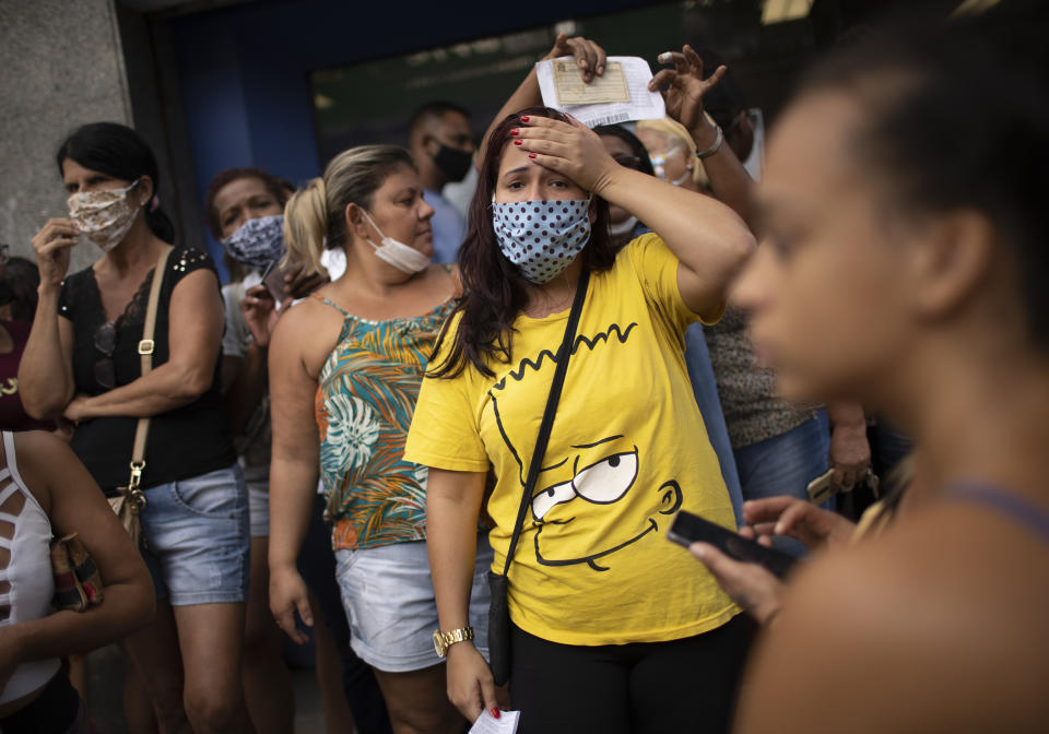 People out of work wait outside a government-run bank having technical problems to distribute their aid money amid the new coronavirus pandemic's affect on the economy in Rio de Janeiro, Brazil, Tuesday, April 28, 2020. (AP Photo/Silvia Izquierdo)