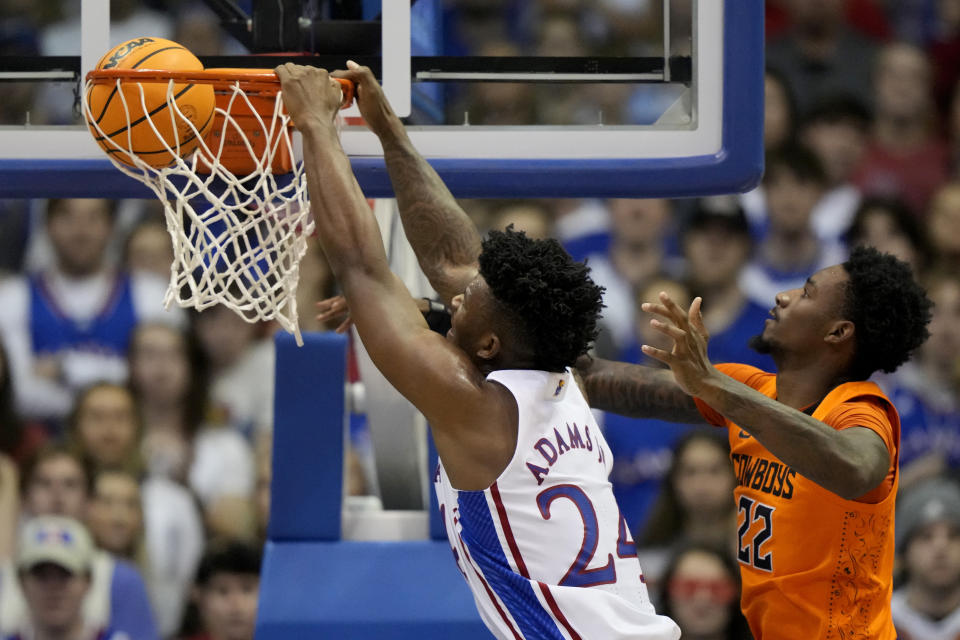 Kansas forward K.J. Adams Jr. (24) gets past Oklahoma State forward Kalib Boone (22) to dunk the ball during the second half of an NCAA college basketball game Saturday, Dec. 31, 2022, in Lawrence, Kan. Kansas won 69-67. (AP Photo/Charlie Riedel)