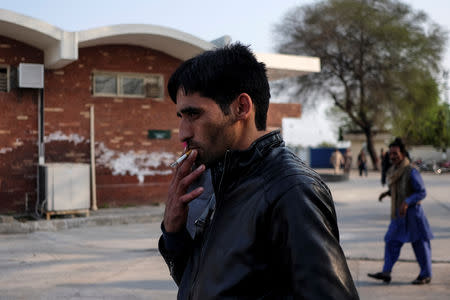Hilal Ahmad Mir, an Indian Kashmiri passenger on the 'friendship bus' running between India and Pakistan, smokes a cigarette after passing through immigration checks at the Wagah-Attari border crossing, Pakistan, March 15, 2019. REUTERS/Alasdair Pal
