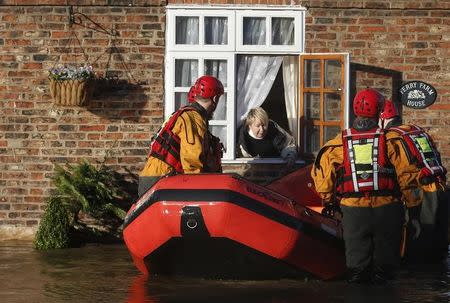 Members of the emergency services rescue a woman from a flooded street in Naburn, northern England, December 27, 2015. REUTERS/Phil Noble