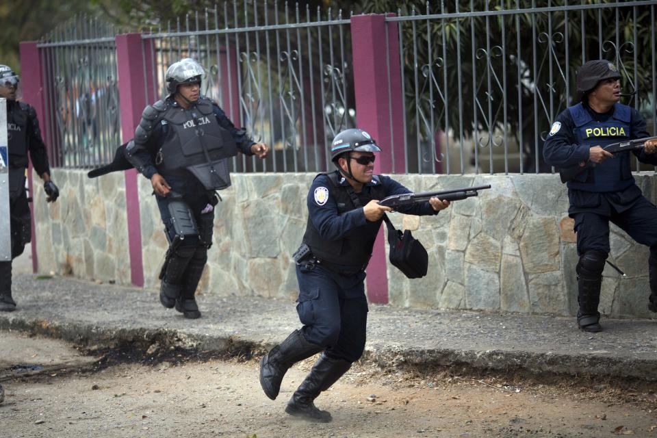 Un policía dispara su arma para dispersar a los opositores, durante un enfrentamiento con la policía en la protesta contra el gobierno de Nicolás Maduro, en Valencia Venezuela, el miércoles 26 de febrero de 2014. Las protestas iniciaron con estudiantes en distintas ciudades, quienes están molestos por el crimen, los problemas económicos y la mano dura con la que la policía les ha respondido. (AP Photo/Rodrigo Abd)