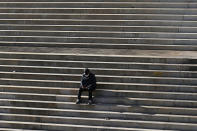 A man wearing a face mask to help curb the spread of the coronavirus sits on a set of stairs in Seoul, South Korea, Monday, Nov. 23, 2020. (AP Photo/Lee Jin-man)