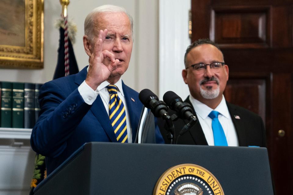 President Joe Biden speaks in August while Education Secretary Miguel Cardona listens at right.