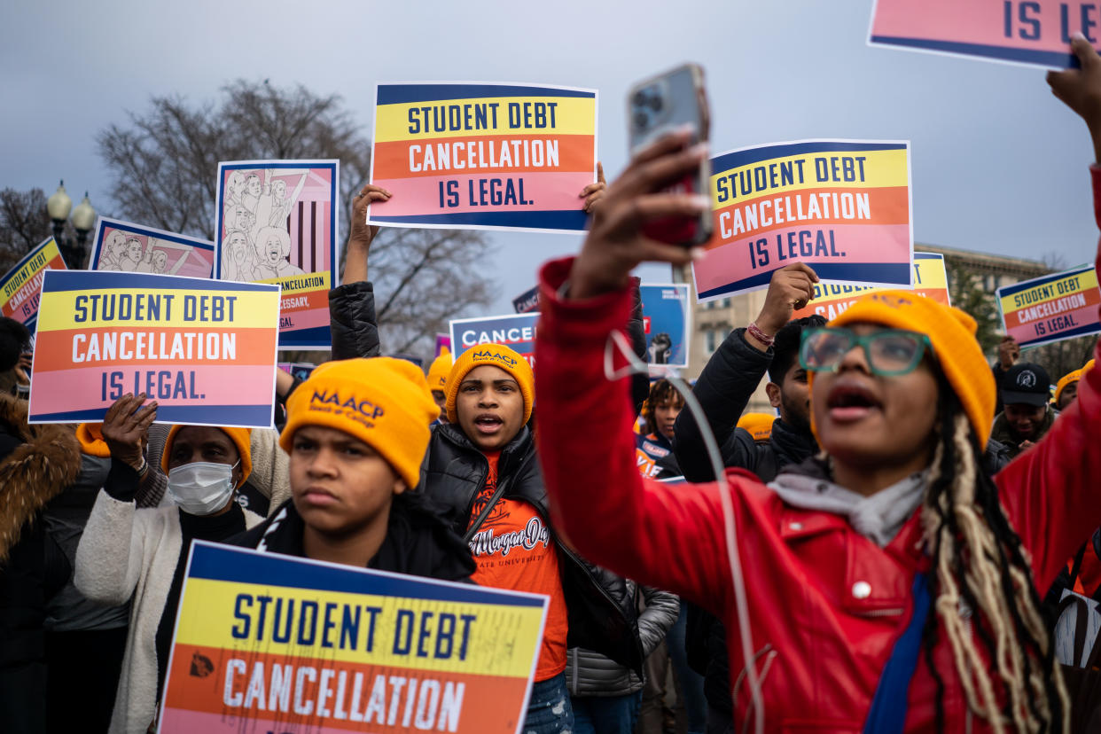 People rally to show support for the student debt relief plan, holding signs that read: Student debt cancellation is legal.