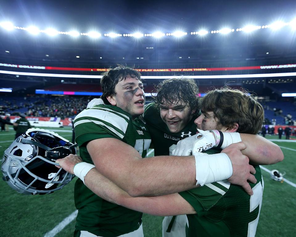 Duxbury's Thomas Sheehan, Duxbury's Alexander Barlow, and Duxbury's Andrew Hunt embrace following their 42-7 win over Grafton in the Division 4 Super Bowl at Gillette Stadium in Foxborough on Friday, Dec. 2, 2022. 