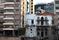 In this February 18, 2014 photo, an old abandoned building with a traditional red brick roof, right, is overshadowed by newly-built apartment buildings, in Beirut, Lebanon. One by one, the old traditional houses of Beirut are vanishing as luxury towers sprout up on every corner, altering the city's skyline almost beyond recognition amid an ongoing construction frenzy. While Lebanon's real estate sector has developed to become one of the country's success stories, many say it is coming at the expense of Lebanon's identity and heritage. (AP Photo/Hussein Malla)