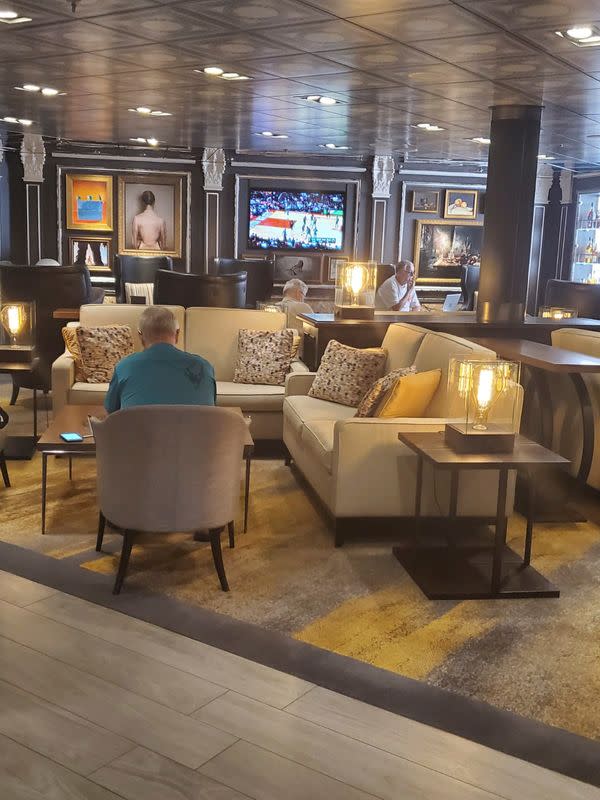 Passengers of Holland America's cruise ship MS Westerdam watch a sports broadcast on the vessel