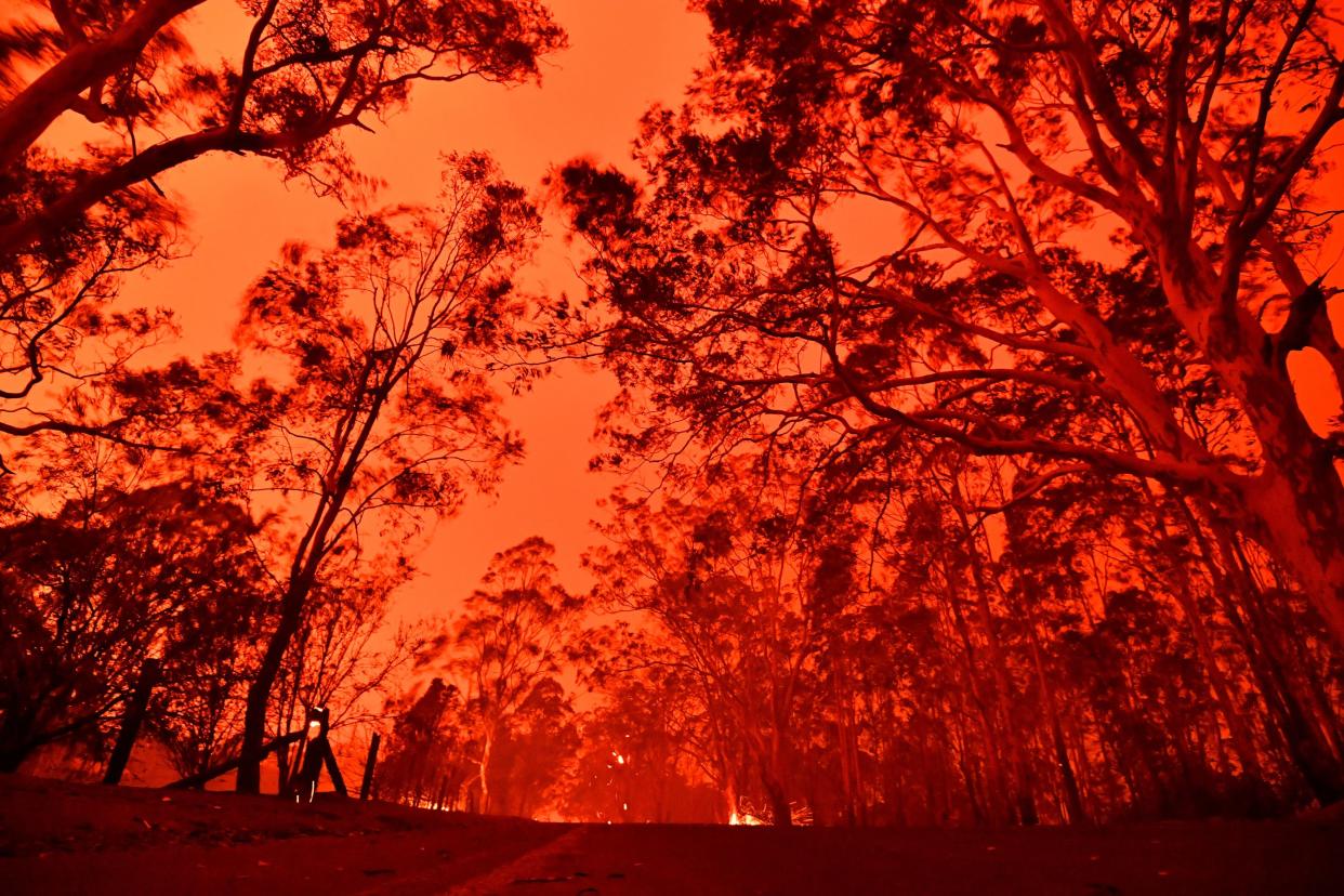 TOPSHOT - The afternoon sky glows red from bushfires in the area around the town of Nowra in the Australian state of New South Wales on December 31, 2019. - Thousands of holidaymakers and locals were forced to flee to beaches in fire-ravaged southeast Australia on December 31, as blazes ripped through popular tourist areas leaving no escape by land. (Photo by SAEED KHAN / AFP) (Photo by SAEED KHAN/AFP via Getty Images)
