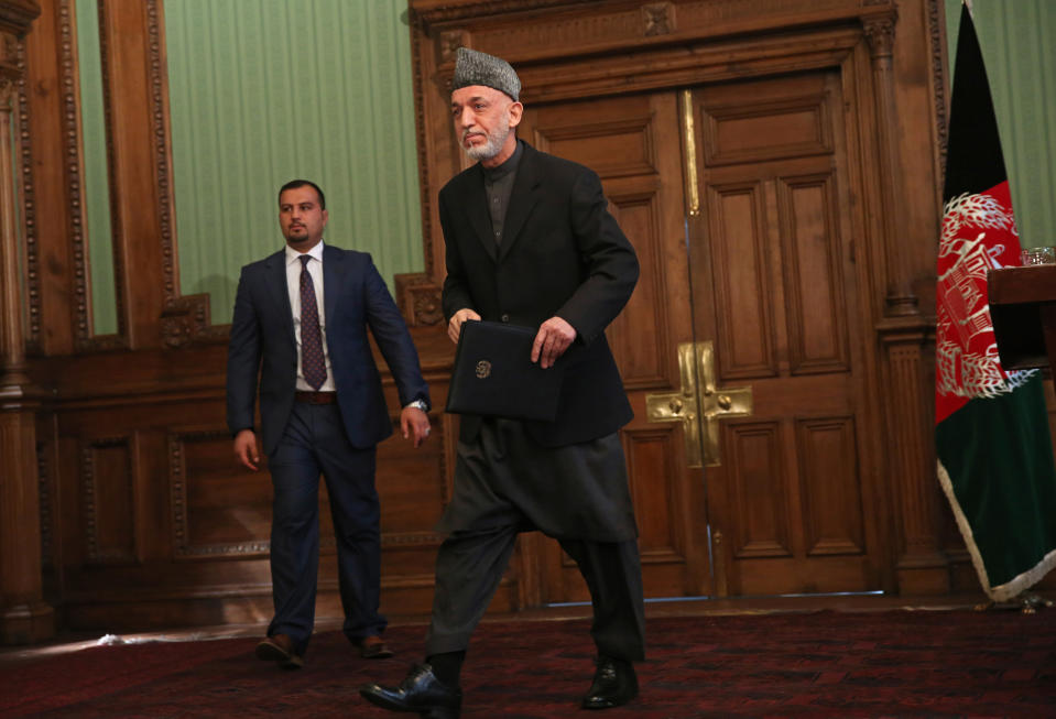 Afghan President Hamid Karzai leaves a press conference at the presidential palace in Kabul, Afghanistan, Saturday, Jan. 25, 2014. Karzai said he will not sign a security pact with the United States unless Washington and Pakistan launch a peace process with Taliban insurgents. (AP Photo/Massoud Hossaini)