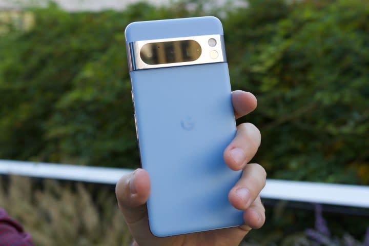 Someone holding the blue Pixel 8 Pro outdoors.