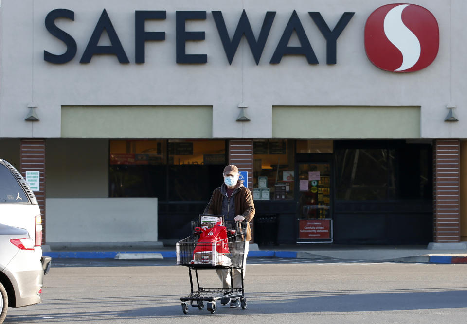 Wearing a mask for protection against the coronavirus, Henry Powell, heads to his car after shopping at a Safeway store in Sacramento, Calif., Thursday, March 19, 2020. Safeway is among the stores that are offering special shopping hours for seniors, like Powell, who is in his 70's, to get their groceries before opening to the rest of the public. (AP Photo/Rich Pedroncelli)