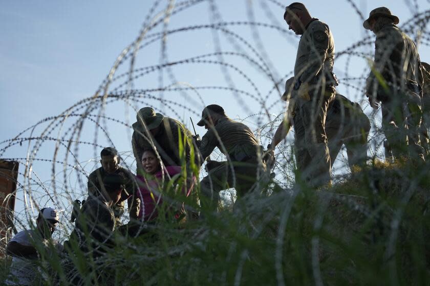 Migrants navigate around concertina wire along the banks of the Rio Grande after crossing from Mexico into the U.S., Tuesday, Aug. 1, 2023, in Eagle Pass, Texas. Concertina wire and newly place buoys being used as a floating barrier, are making in more difficult and dangerous to cross the Rio Grande. (AP Photo/Eric Gay)