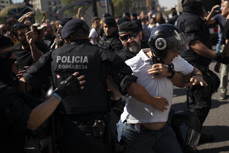 A pro independence demonstrator is blocked by Catalan police officers as he tries to reach a protest of members and supporters of National Police and Guardia Civil demanding better pay in Barcelona, Spain, Saturday, Sept. 29, 2018. (AP Photo/Felipe Dana)