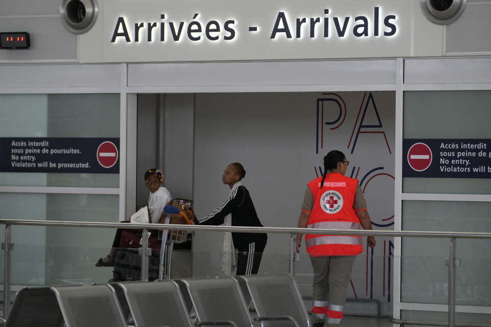 A worker of Red Cross takes care of people evacuated from Niger at the Roissy Charles de Gaulle airport, north of Paris, France, Wednesday, Aug. 2, 2023. European militaries are continuing to evacuate foreign nationals from Niger, with a third French military flight expected to depart the African nation's capital. Defense chiefs from West Africa's regional bloc are set to meet to discuss last week's coup against the country's democratically elected president. (AP Photo/Christophe Ena)