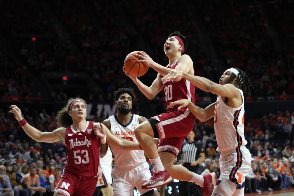 Nebraska's Keisei Tominaga (30) drives to the basket past Illinois' Ty Rodgers, right, and Quincy Guerrier as Josiah Allick (53) watches during second half of an NCAA college basketball game Sunday, Feb. 4, 2024, in Champaign, Ill. (AP Photo/Charles Rex Arbogast)