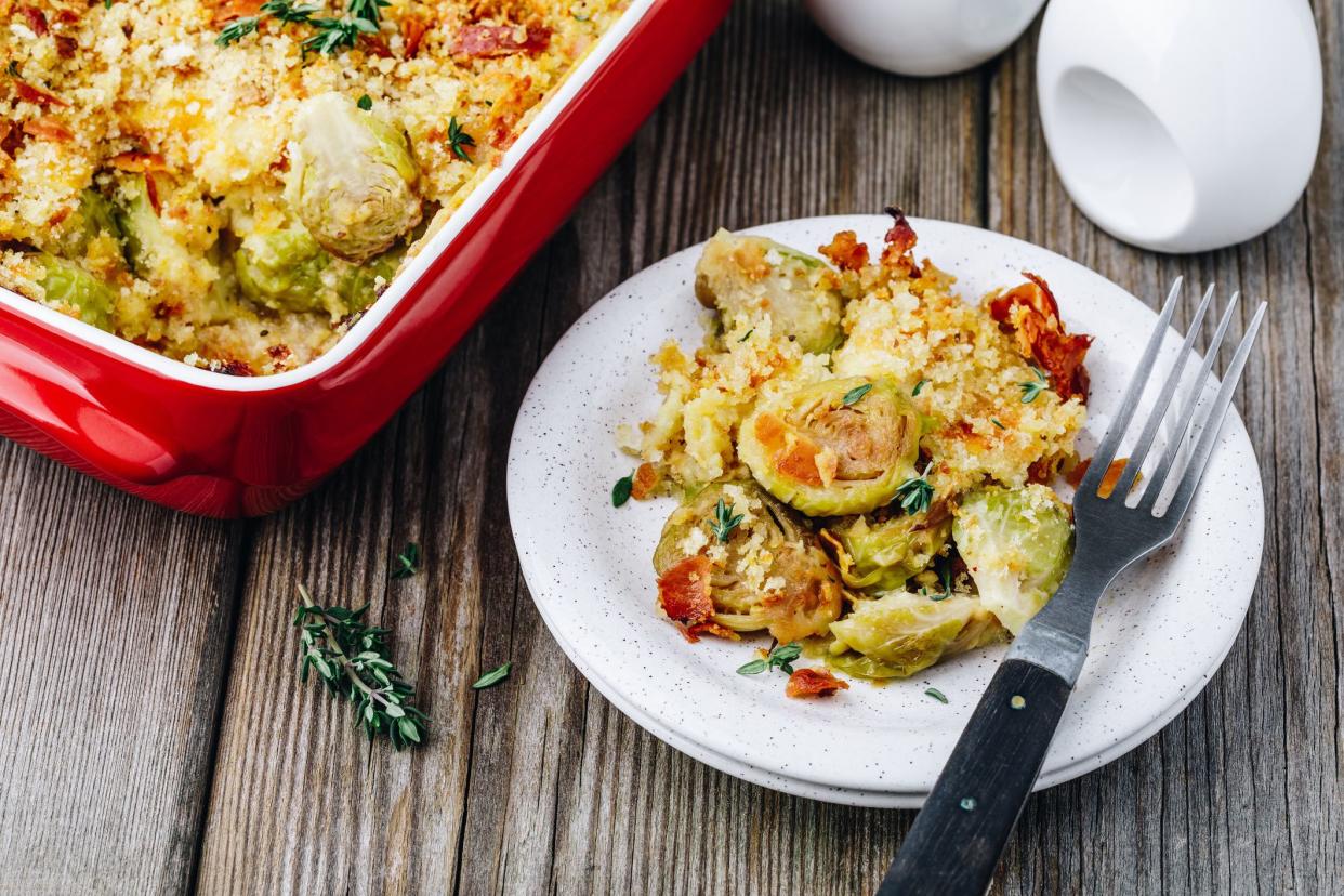 Baked brussel sprout gratin with a bacon and bread crumbs on wooden background